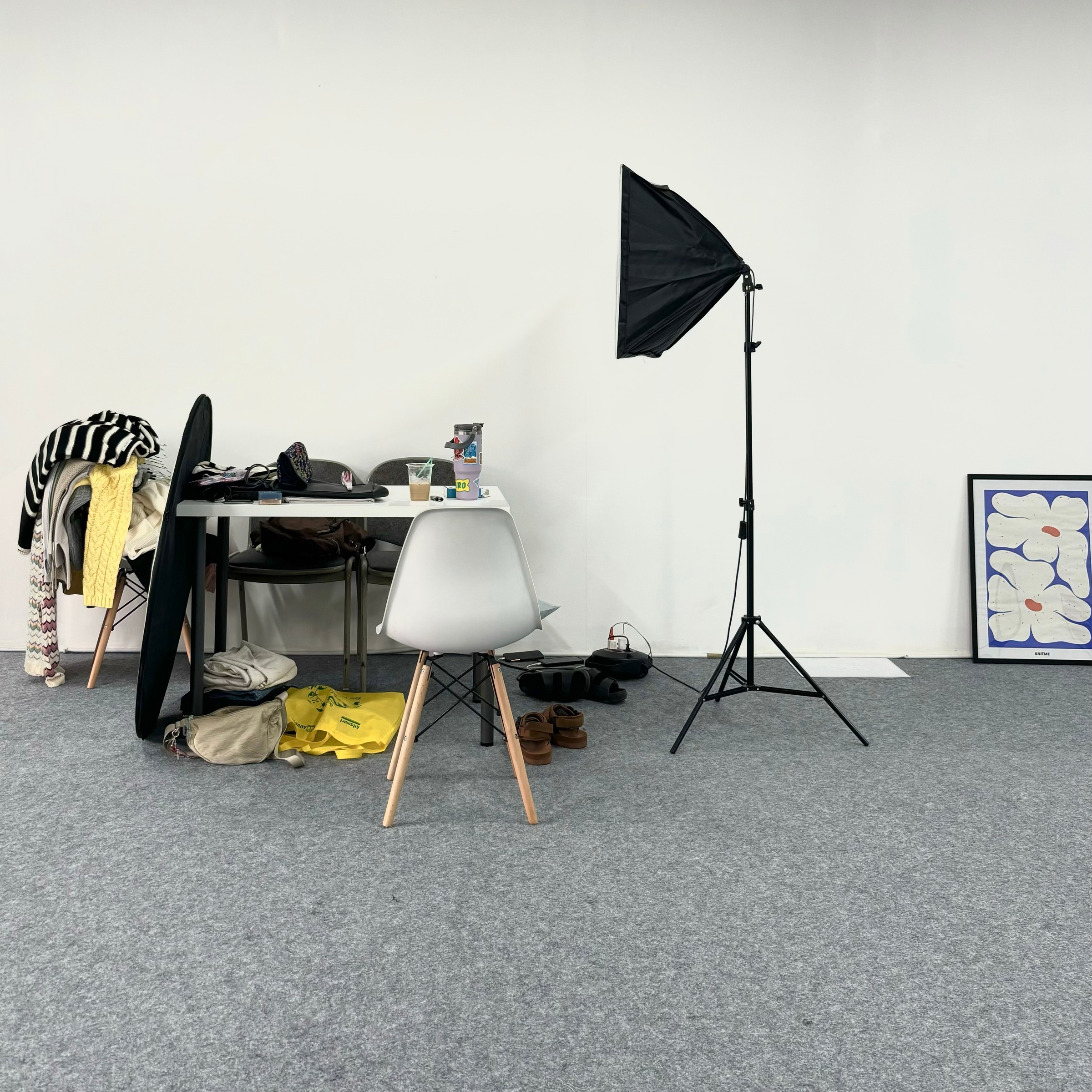 Studio set with a softbox, a chair and racks of knitwear before a shoot